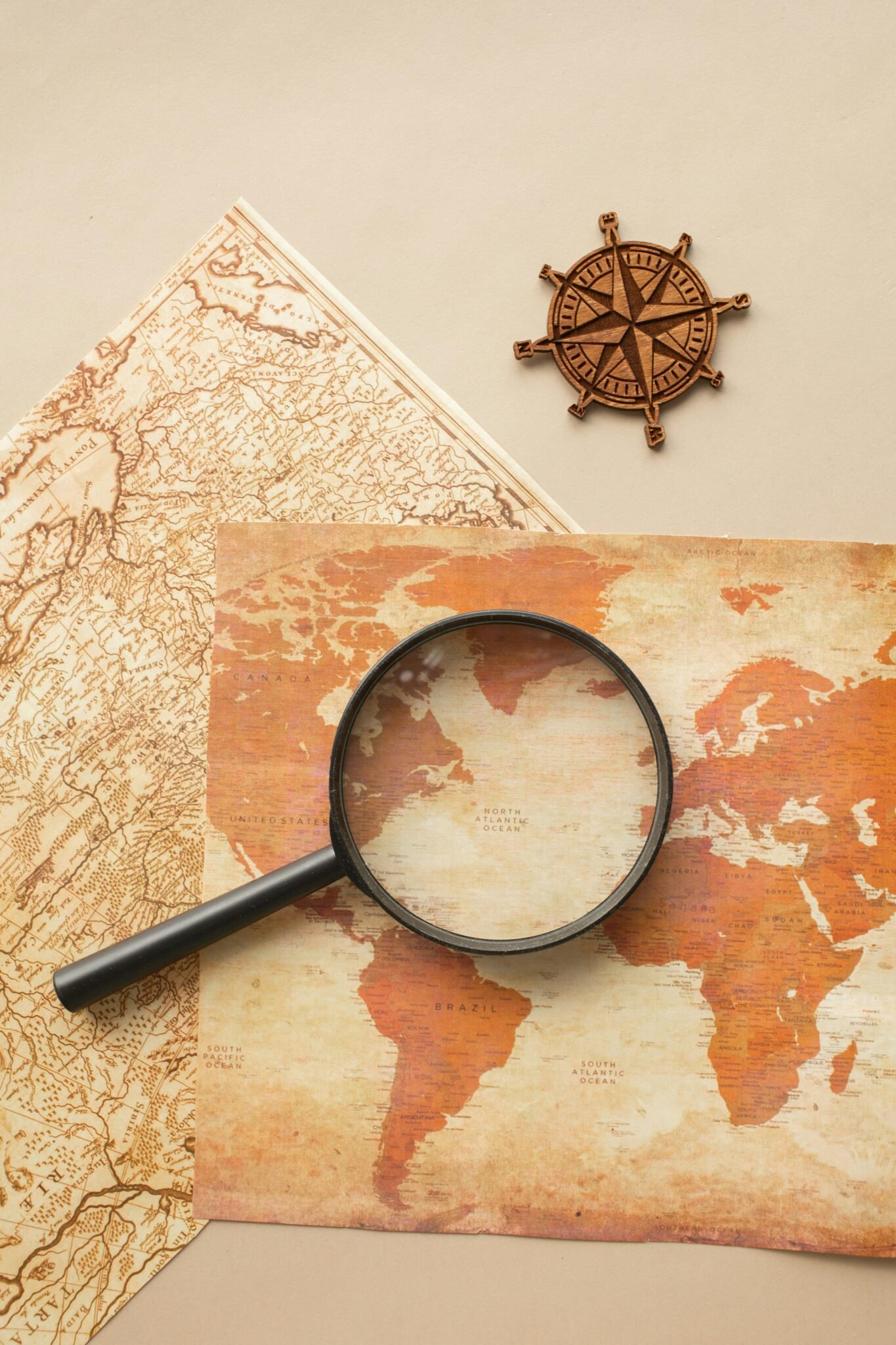 High-angle view of a vintage map with magnifying glass and compass for exploration themes.
